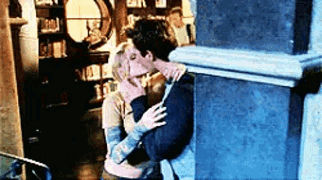 a man and a woman are kissing in front of a book store .