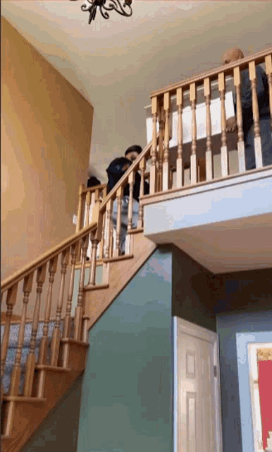 a staircase with a wooden railing and a chandelier above it