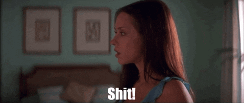 a woman is standing in front of a bed and says shit !
