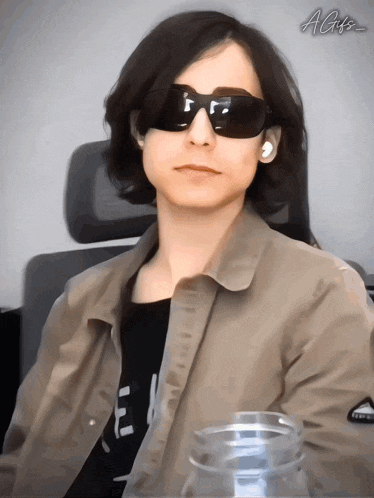 a person wearing sunglasses and a jacket with the letters agz on the bottom right