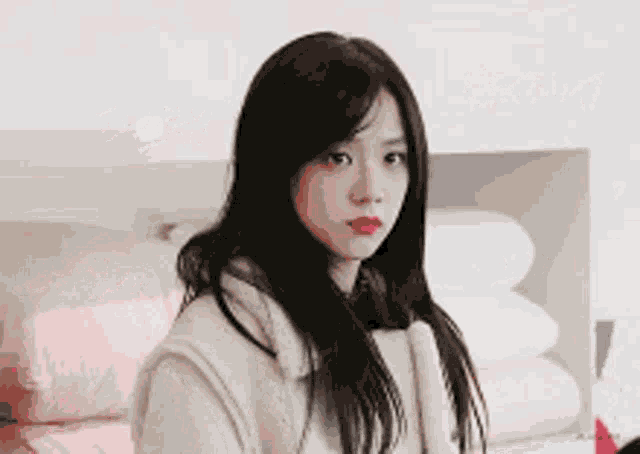 a woman with long black hair and red lipstick is looking at the camera .