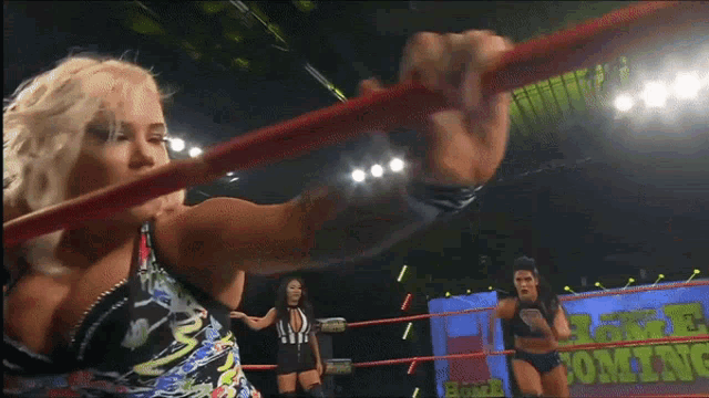 two women wrestling in a ring with a sign that says coming
