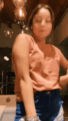 a woman in a pink tank top and blue shorts is standing in front of a mirror .