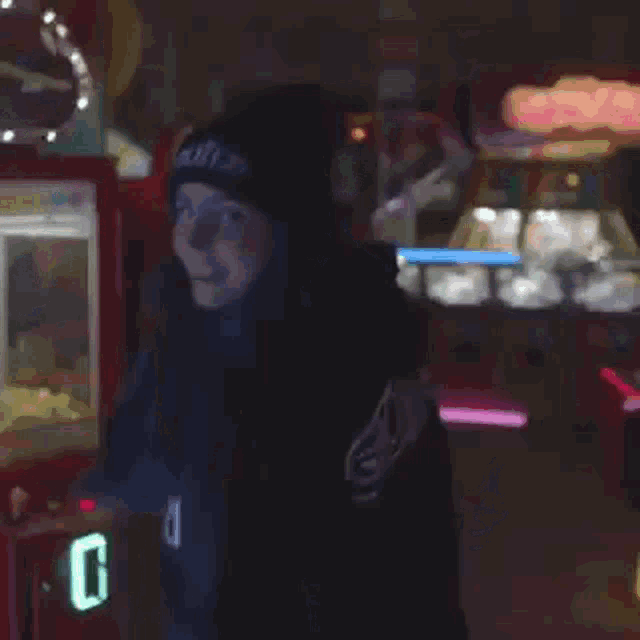 a person wearing a black hoodie with the word rolling on it is standing in a dark room .