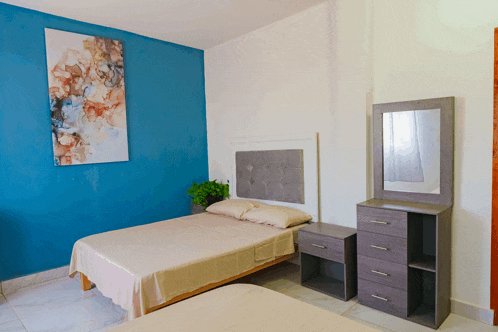 a bedroom with two beds a nightstand a mirror and a blue wall