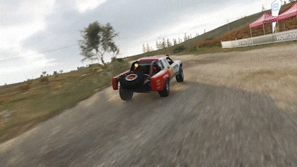 a red and white truck is driving down a dirt road in front of a horizon sign