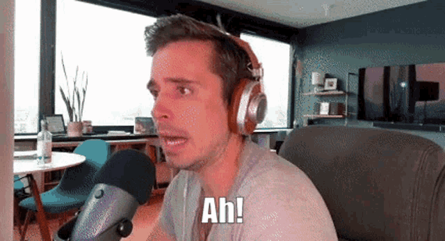 a man wearing headphones is sitting in front of a microphone and says ah