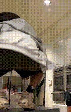 a person is standing in a kitchen wearing a hoodie and shorts