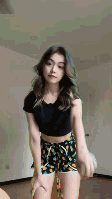 a woman in a black shirt and shorts is dancing in a room