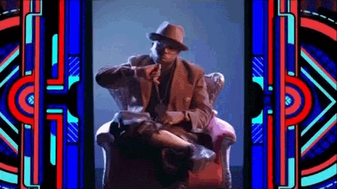 a man in a suit and hat is sitting in a chair in front of a stained glass window
