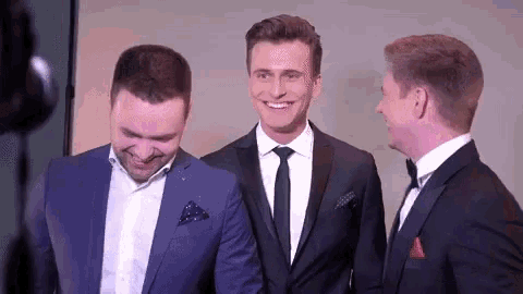 three men in suits and ties are standing next to each other smiling .