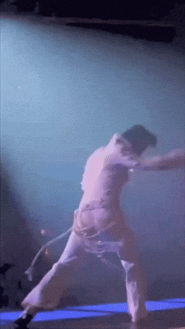 a person is dancing on a stage with a purple background