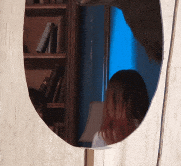 a woman with red hair is reflected in a mirror in a room