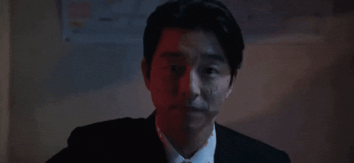 a man in a suit is pointing a gun at his head .
