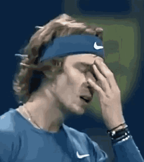 a tennis player is covering his face with his hand .