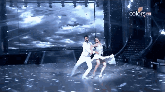 a man and a woman are dancing on a stage with the words colors hd on the bottom right