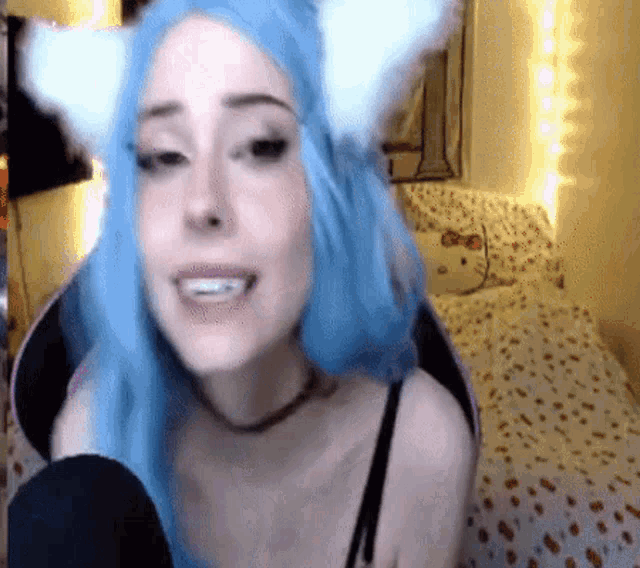 a woman with blue hair and white cat ears is smiling