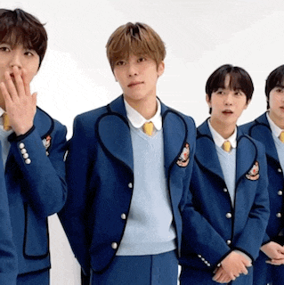 a group of young men wearing blue suits and sweaters are standing next to each other .