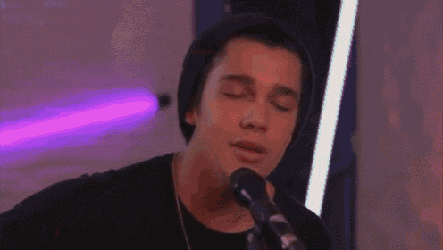 a young man singing into a microphone wearing a black beanie