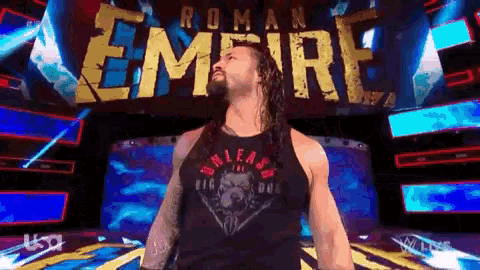 roman reigns is standing in front of the roman empire banner