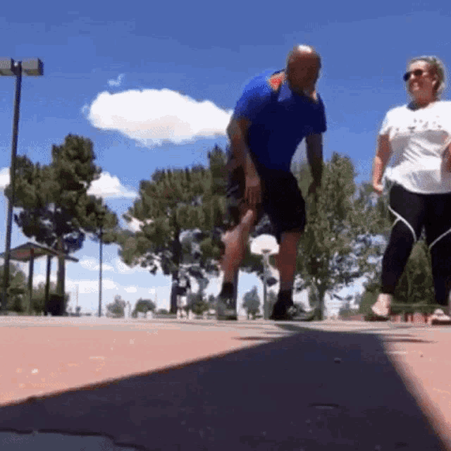 a man in a blue shirt is doing a trick while a woman watches