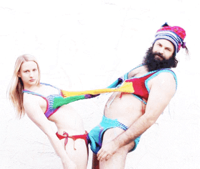 a man with a beard is holding a woman 's arm in a bikini