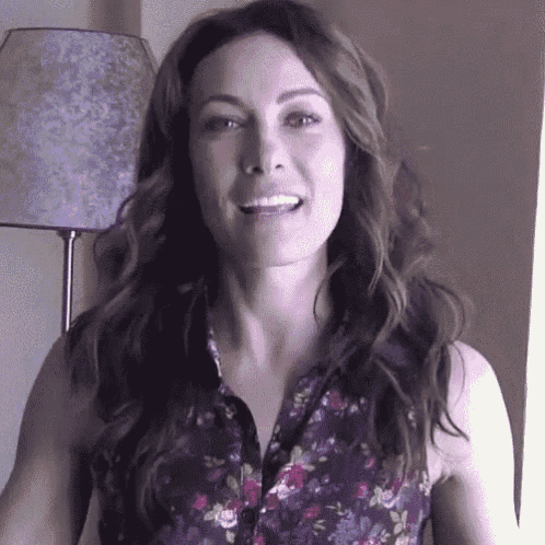 a woman in a floral shirt is smiling and looking at the camera .