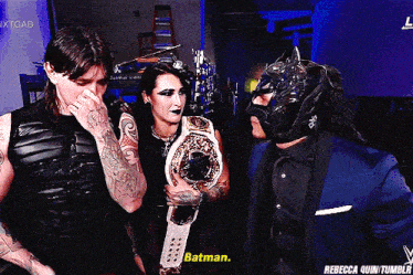 a man in a batman mask talks to a woman holding a belt