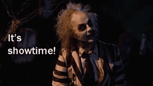 a man in a striped suit and tie is standing in the dark and saying it 's showtime .