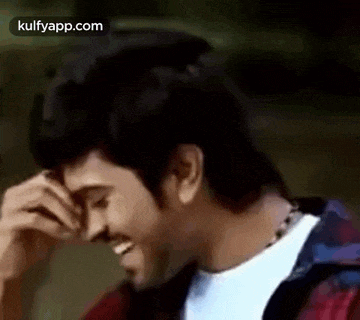 a man is covering his face with his hand while laughing .