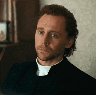 a man with a beard is wearing a black suit and white collared shirt .