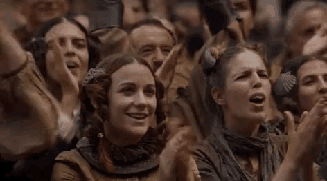 a group of people are sitting in a room applauding and smiling .