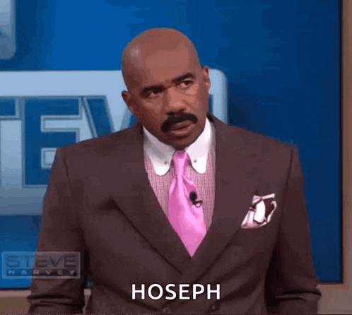a man in a suit and tie is standing in front of a blue wall and says hoseph .