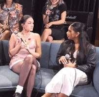 a group of women are sitting on a blue couch talking to each other