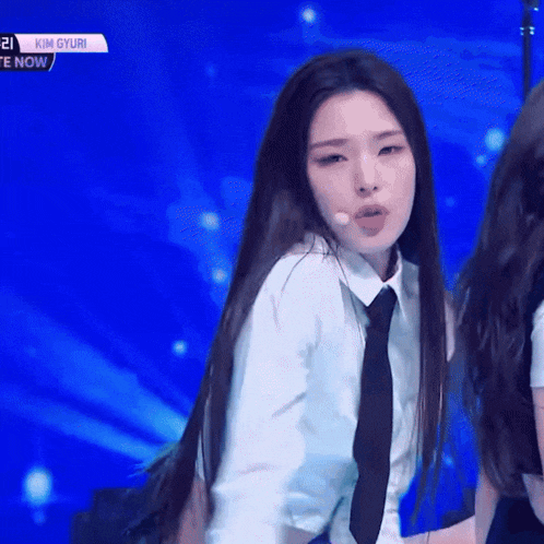 a girl in a white shirt and tie is dancing on a stage with the words kim gyuri written on the bottom