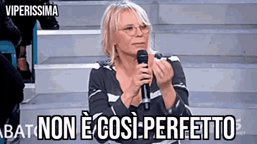 a woman wearing glasses is holding a microphone and saying non e così perfetto