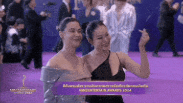 two women are posing for a picture on a purple carpet that says nineentertainment awards 2024 on it
