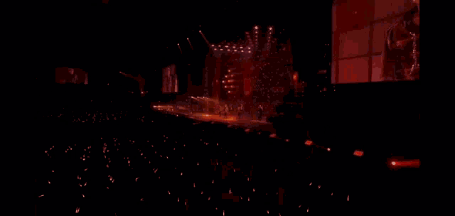a man without a shirt is dancing in a dark room with a red light behind him .