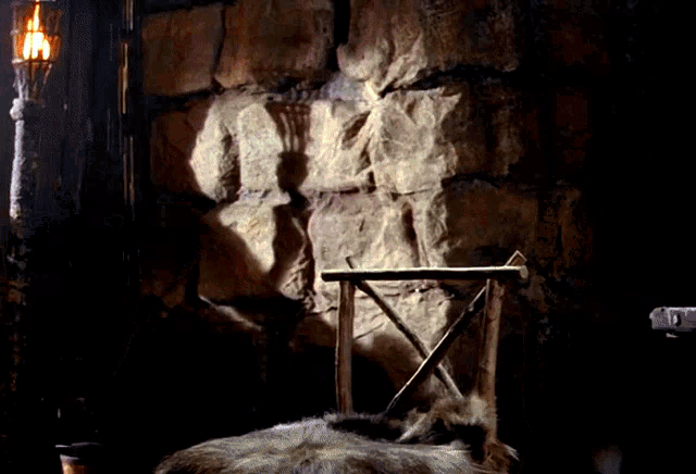 a torch is lit up in a dark room with a chair in the foreground