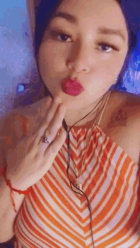 a woman is blowing a kiss while wearing headphones and a ring on her finger .