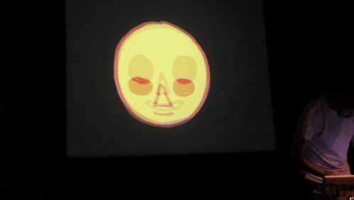 a man stands in front of a projection of a smiley face on a screen