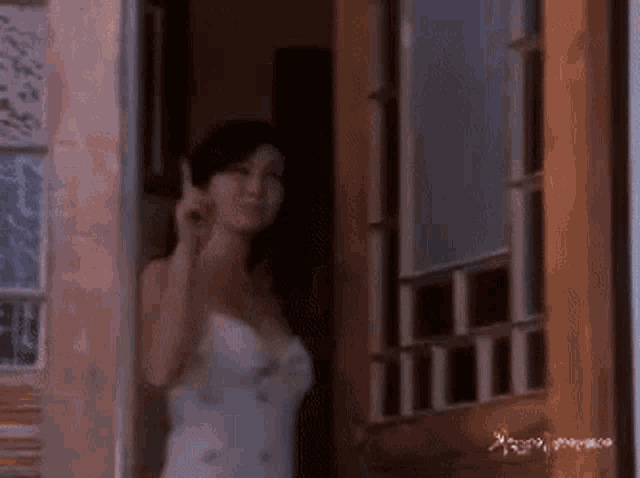 a woman in a white dress is standing in front of a door