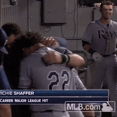 a baseball player is hugging another player in a dugout .