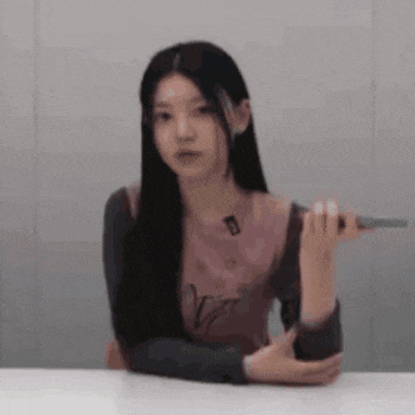a young woman is sitting at a table holding a microphone .