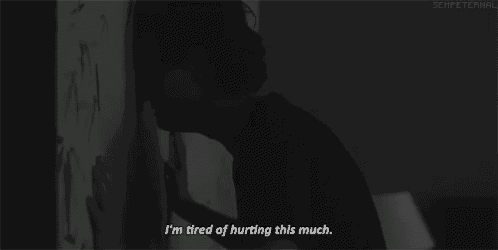 a black and white photo of a man leaning against a wall with the words `` i 'm tired of hurting this much ''