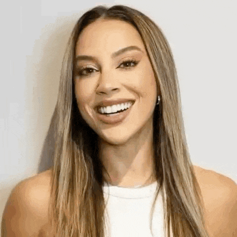 a woman with long hair is smiling and wearing a white shirt .