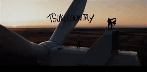 a couple standing on top of a wind turbine with the words tsuki country written in the background