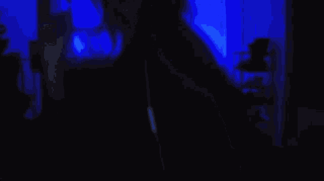 a woman is standing in a dark room with blue lights behind her