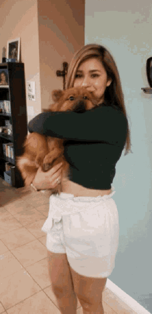 a woman holds a small dog in her arms