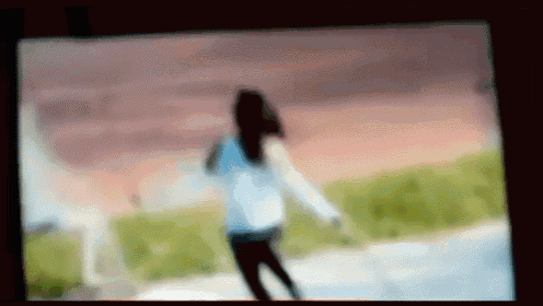 a blurry picture of a girl standing in front of a sunset